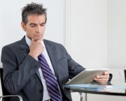 Contemplative Businessman Using Digital Tablet In Office