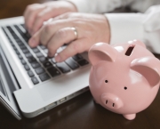 Piggy Bank Near Male Hands Typing on Laptop