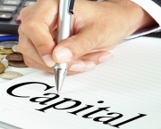 Hand with pen pointing to Capital word on the paper - business & financial concept
