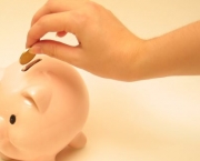 hand placing coin in piggy bank